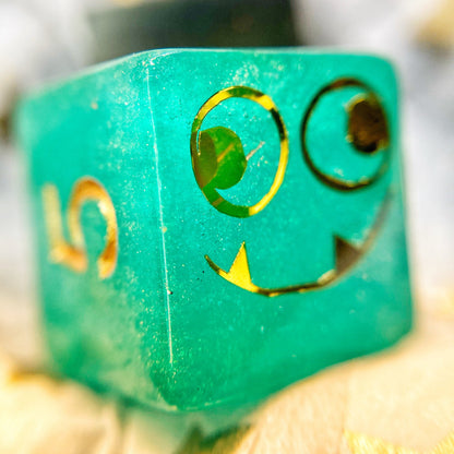 Tusktooth Fjord Inspired D6 – Handmade Glow-in-the-Dark Green & Blue Gaming Die with Gold Grinning Face