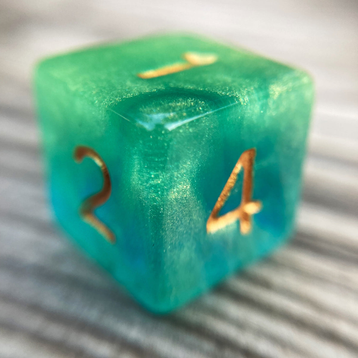 Tusktooth Fjord Inspired D6 – Handmade Glow-in-the-Dark Green & Blue Gaming Die with Gold Grinning Face