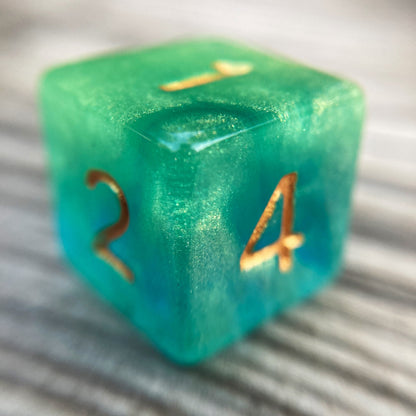 Tusktooth Fjord Inspired D6 – Handmade Glow-in-the-Dark Green & Blue Gaming Die with Gold Grinning Face